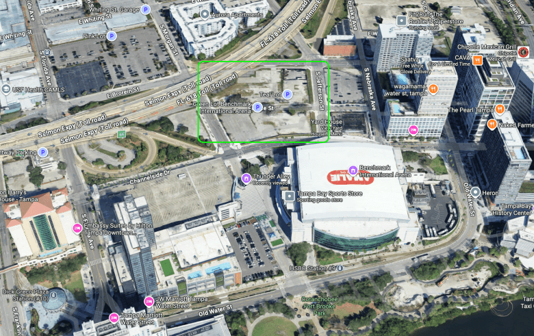n aerial satellite image from Google Maps showing a busy urban section of downtown Tampa. A green rectangle highlights a large, mostly empty paved lot located between the Selmon Expressway and the massive Amalie Arena, which is labeled as "Benchmark International Arena."
